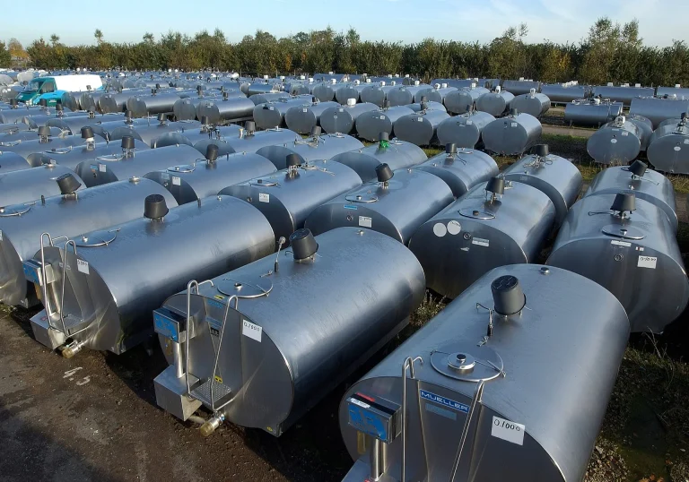 Mehrere gebrauchte Milchtanks aus Edelstahl im Lager, seitlich fotografiert